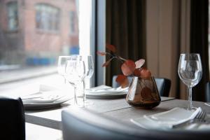 uma mesa de madeira com óculos e um vaso com uma planta em Henriks Hotell em Skien