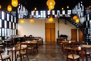 un restaurant avec des tables en bois, des chaises et des lumières dans l'établissement Front One Hotel Gombong, à Gombong