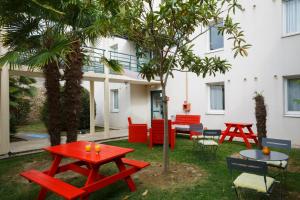 a patio with red tables and chairs in front of a building at B&B HOTEL Les Sables-d'Olonne Centre Gare in Les Sables-d'Olonne