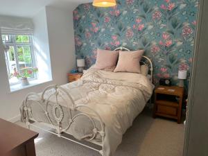 a bedroom with a bed with a floral wallpaper at Character Cottage in Gunnislake in Gunnislake