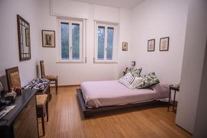a bedroom with a bed and a desk and two windows at Casa Gioia in Nebbiuno