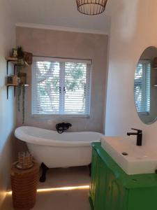 a bathroom with a tub and a sink and a window at 1 Croft Cottage, in Knysna