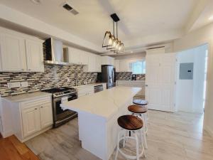 uma cozinha branca com um balcão e bancos em Coastal-Inspired Home near Beach & Village em San Diego