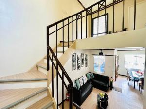 a living room with a black couch and stairs at Hidden Gem: Cebu's Best Escape in Talisay