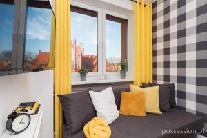 um sofá num quarto com janelas e um relógio em Mikrokawalerki w sercu Gdańska em Gdansk