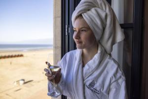 Eine Frau mit einem Handtuch auf dem Kopf, die ein Glas Wein hält in der Unterkunft Hotel Villa Select in De Panne