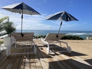twee stoelen en parasols op een terras met het strand bij La Sirena del Viento in Los Caños de Meca
