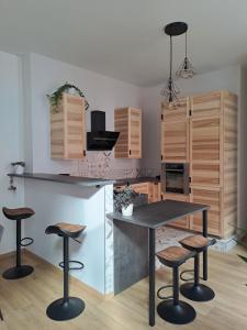 a kitchen with a table and four bar stools at Le Q'vier in Montbéliard