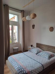 a bedroom with a bed with a blue comforter and a window at Le Q'vier in Montbéliard