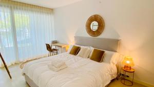 a bedroom with a large white bed with a mirror at Casa de la Risa - Sotogrande house with rooftop pool in San Enrique de Guadiaro