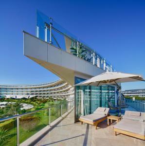 a glass building with two chairs and an umbrella at Maxx Royal Belek Golf Resort in Belek