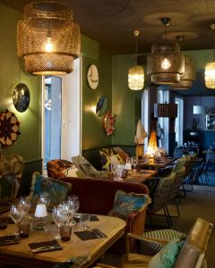 um restaurante com mesas longas, cadeiras e lustres em Hôtel des Pins em Jullouville-les-Pins