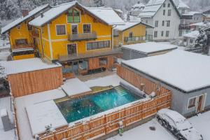 une maison avec une piscine dans la neige dans l'établissement AlpinSpa zur Post, à Bad Gastein