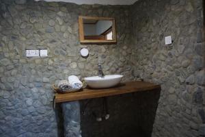 a bathroom with a sink and a stone wall at Cocoa Village Guesthouse in Obo