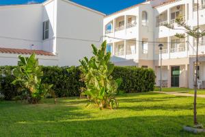 a large white building with a green yard at Cala en Blanes Park in Cala en Blanes
