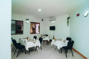 un comedor con mesas blancas y sillas negras en Arusha Giraffe Lodge, en Arusha