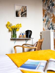 uma mesa com um vaso de flores amarelas na parede em Hôtel des Pins em Jullouville-les-Pins