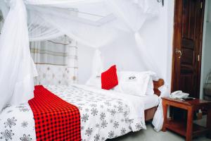 Schlafzimmer mit einem Bett mit einer roten und weißen Decke in der Unterkunft Arusha Giraffe Lodge in Arusha