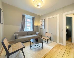 een woonkamer met een bank, stoelen en een tafel bij Rustic & Cozy 2BR in Heart of CPH City by Strøget in Kopenhagen