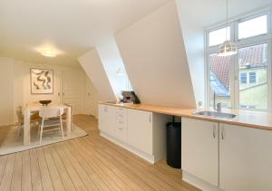 een keuken met witte kasten, een wastafel en een tafel bij Rustic & Cozy 2BR in Heart of CPH City by Strøget in Kopenhagen