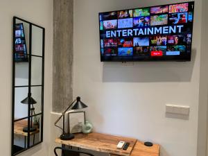 - une télévision murale dans une chambre avec une table dans l'établissement La Reina Beach rooms, à Valence