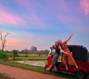 Due donne sono in piedi sul retro di un furgone rosso. di Lucky Villa Sigiriya a Sigiriya