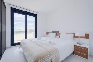 a bedroom with a large bed with a large window at Apartament Sea Senses Summer in Punta Prima +30 photos