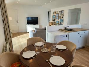 Una mesa de comedor con sillas y una cocina. en Gîte Les Pirouettes, en Pirou