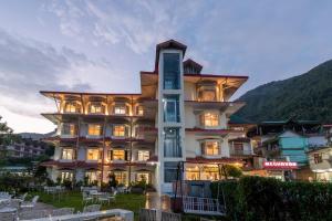 a large building with lights on in front of a mountain at Meghavan Resort By DLS Hotels in Dharamshala