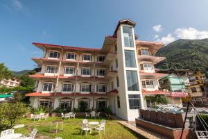 a large building with tables and chairs in front of it at Meghavan Resort By DLS Hotels in Dharamshala