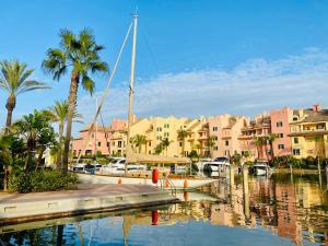 a boat docked at a marina with palm trees and buildings at Casa de la Risa - Sotogrande house with rooftop pool in San Enrique de Guadiaro