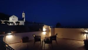 een tafel en stoelen op een balkon in de nacht bij Scappo in Umbria, La casa di Eude in Assisi