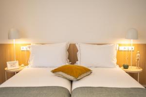 un letto con lenzuola bianche e un cuscino marrone di Watts House a Seia