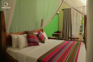 a bedroom with a large bed with colorful pillows at Kabalega Resort - Hoima in Hoima