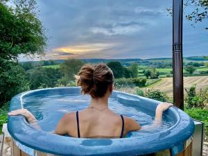 una mujer sentada en una gran piscina inflable en Herefordshire Escape, Hot Tub, Firepit, Views, BBQ en Leominster