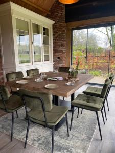 a dining room with a wooden table and chairs at Domestico Bed & Breakfast in Lage Mierde