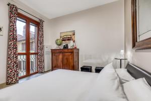 ein Schlafzimmer mit einem weißen Bett und einem Fenster in der Unterkunft ANGOLO DI CORSO CAVOUR - Ultimo piano centrale e luminoso in Pavia