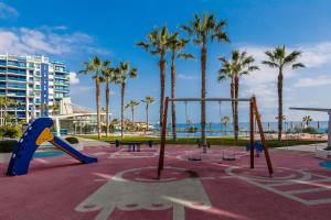 a playground with palm trees and a swing set at Apartament Sea Senses Summer in Punta Prima