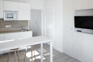 cocina blanca con mesa blanca y TV en Apartamentos Egona Zarautz sobre el mar, en Zarautz