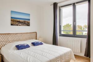 um quarto com uma cama com duas almofadas azuis em Escapade Bretonne pour 4 a Fouesnant em Fouesnant