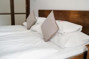 ein Bett mit weißer Bettwäsche und Kissen darauf in der Unterkunft Hotel Staribacher Südsteiermark in Leibnitz