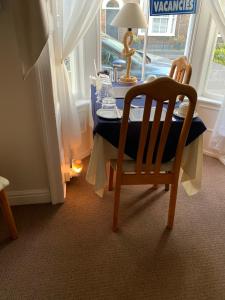 a table with a chair and a lamp in a room at Cunard Guest House in Weymouth +14 photos