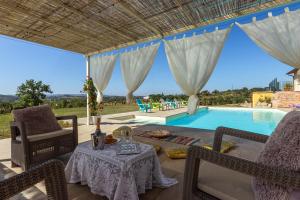 eine Terrasse mit Tisch und Stühlen und einem Pool in der Unterkunft Villa Poggio al Sole by VacaVilla in Foiano della Chiana
