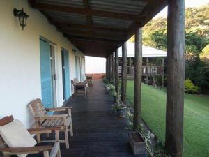 a porch with wooden chairs and tables and a house at Glengariff Lodge in East London