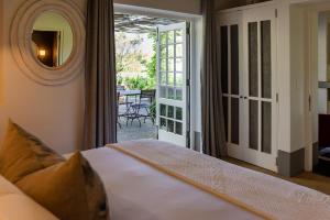 a bedroom with a bed and a door to a patio at Grande Provence in Franschhoek