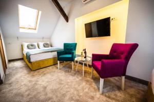 サラエボにあるDeluxe Nortel Hotelの椅子2脚、ベッド1台、テレビが備わる客室です。