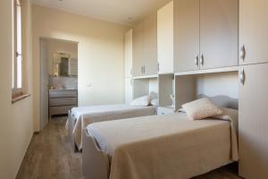 2 Betten in einem Zimmer mit weißen Schränken in der Unterkunft Villa Poggio al Sole by VacaVilla in Foiano della Chiana + 39 Fotos