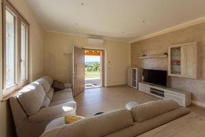 ein Wohnzimmer mit Sofa und Fernseher in der Unterkunft Villa Poggio al Sole by VacaVilla in Foiano della Chiana