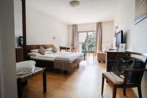 ein Schlafzimmer mit einem Bett, einem Sofa und einem Stuhl in der Unterkunft Hotel Staribacher Südsteiermark in Leibnitz