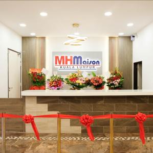 a lobby with flowers on a counter with a sign at Maison Signature Suites in Kuala Lumpur